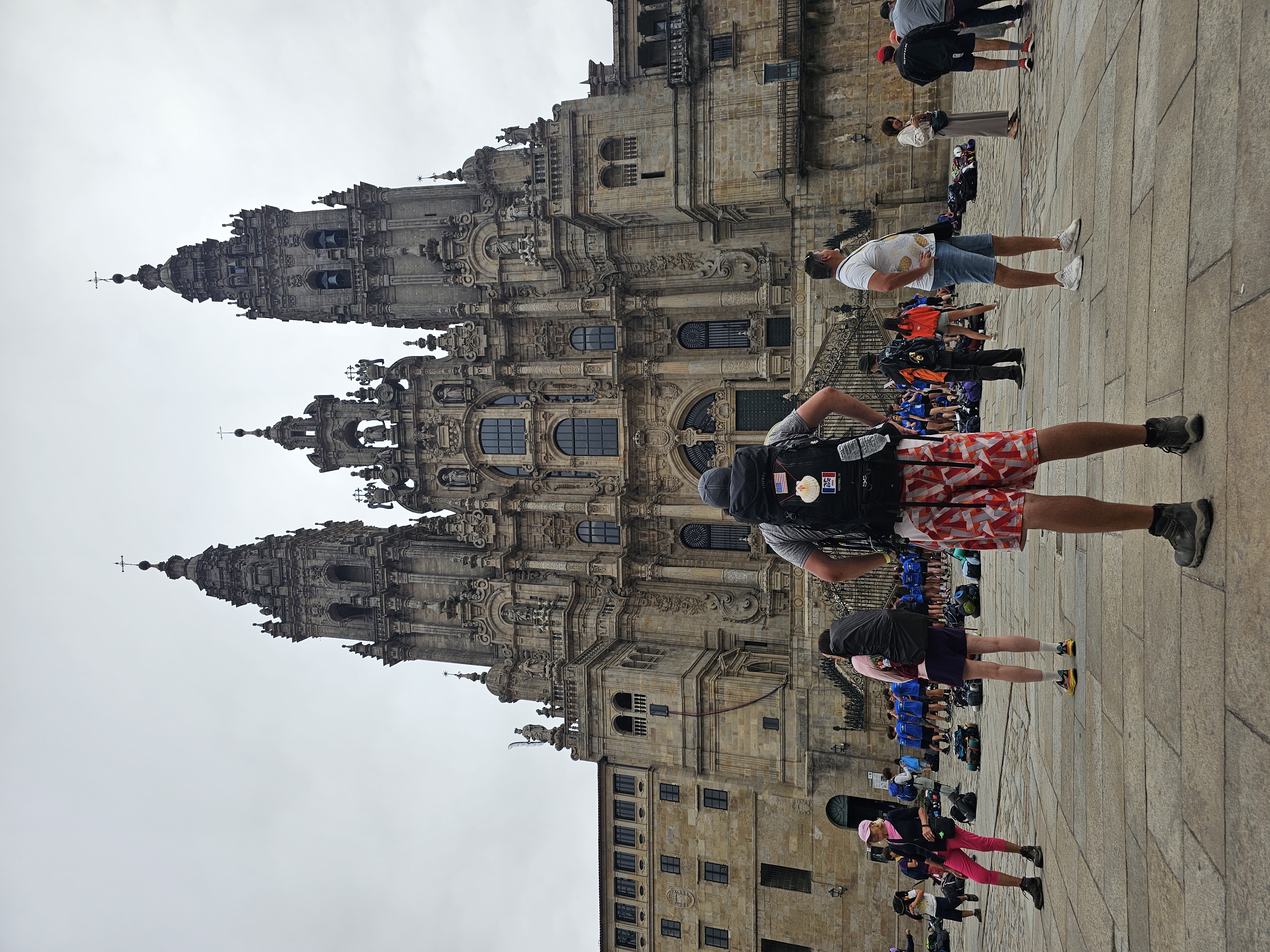 man standing in front of the cathedral de Santiago, back to camera